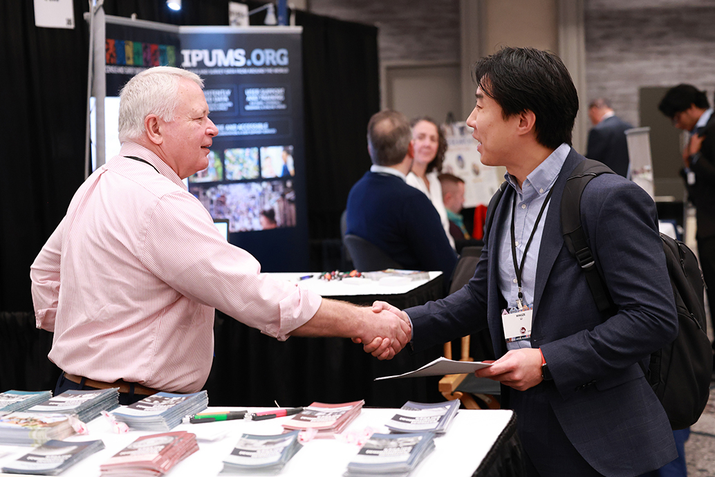 An exhibitor shakes hands with an ASSA event attendee in the Exhibit Hall.